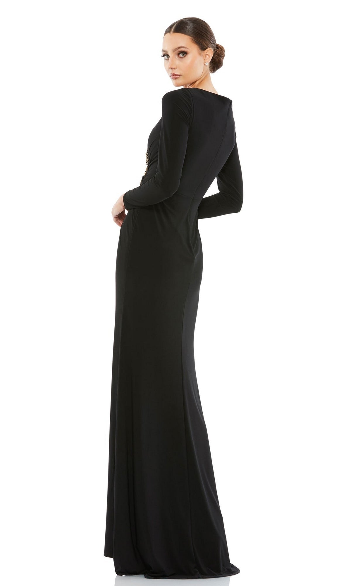 A woman poses elegantly in the Mac Duggal 67848 Long Sleeve Long Formal Dress, standing with her body angled and looking gracefully over her shoulder.